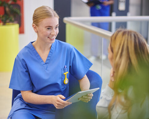 Female nurse talking to a patient in the waiting area